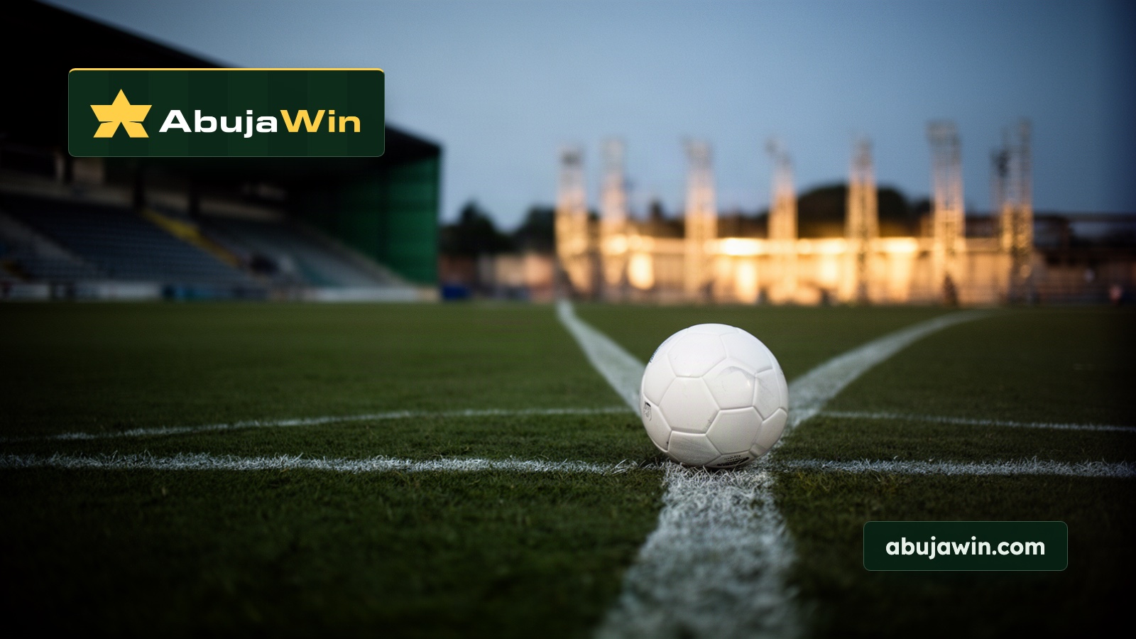 A white match ball resting on the chalk centre spot of a floodlit pitch at blue hour.