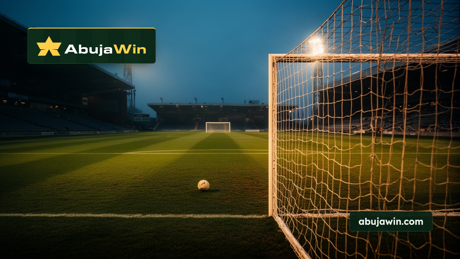 A floodlit football pitch at blue hour seen from behind a goal, with the far goal glowing at the other end of the turf.