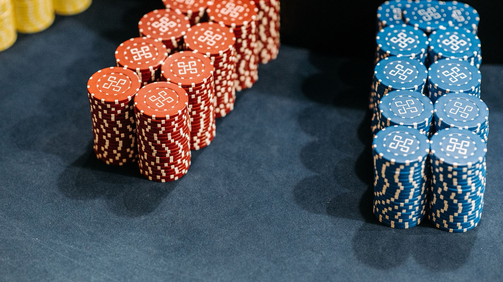 Tall stacks of red and blue casino chips standing on a dark green felt table.