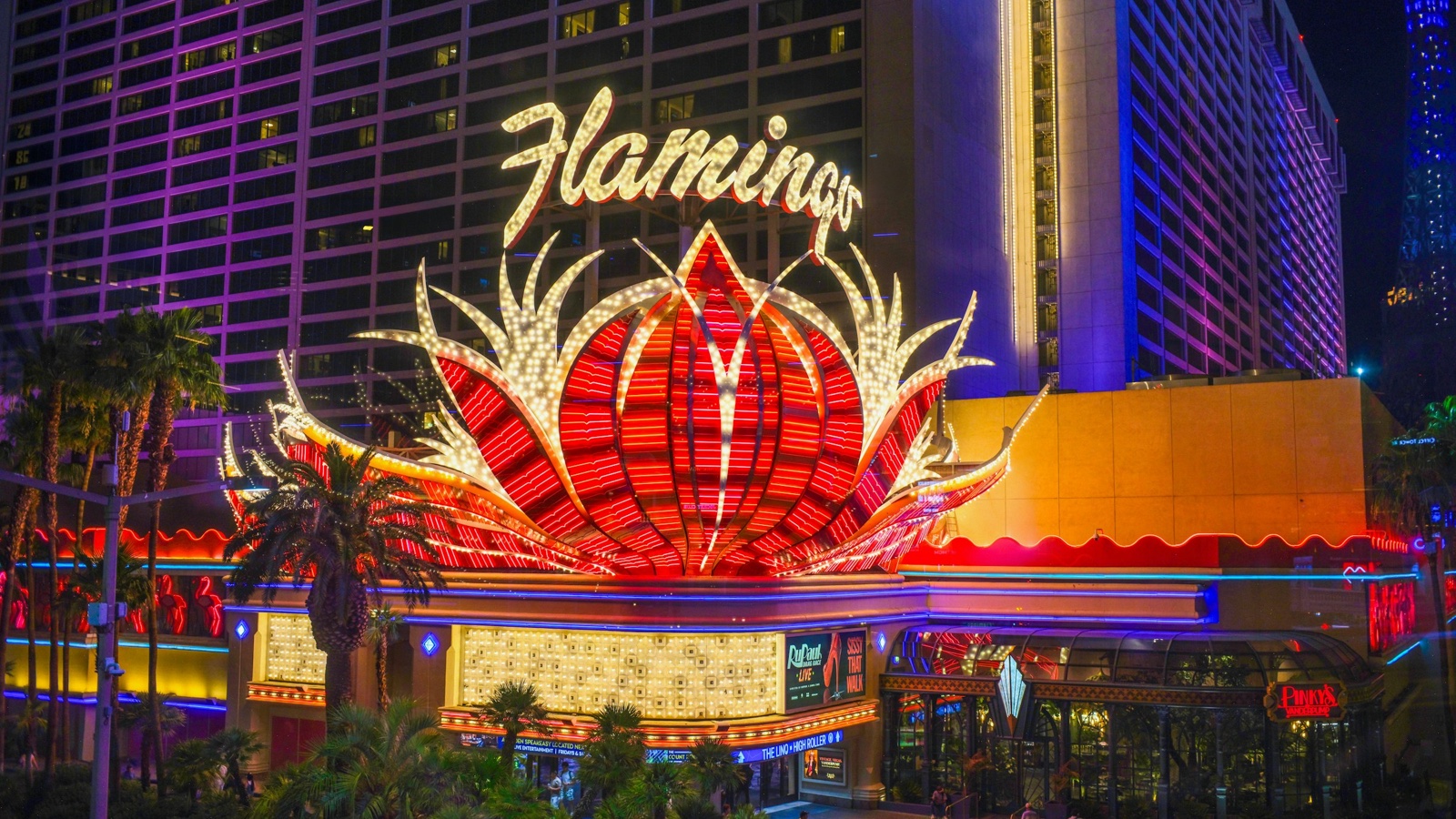 The Flamingo's glowing red and white neon sign shines above its entrance on the Las Vegas Strip at night.