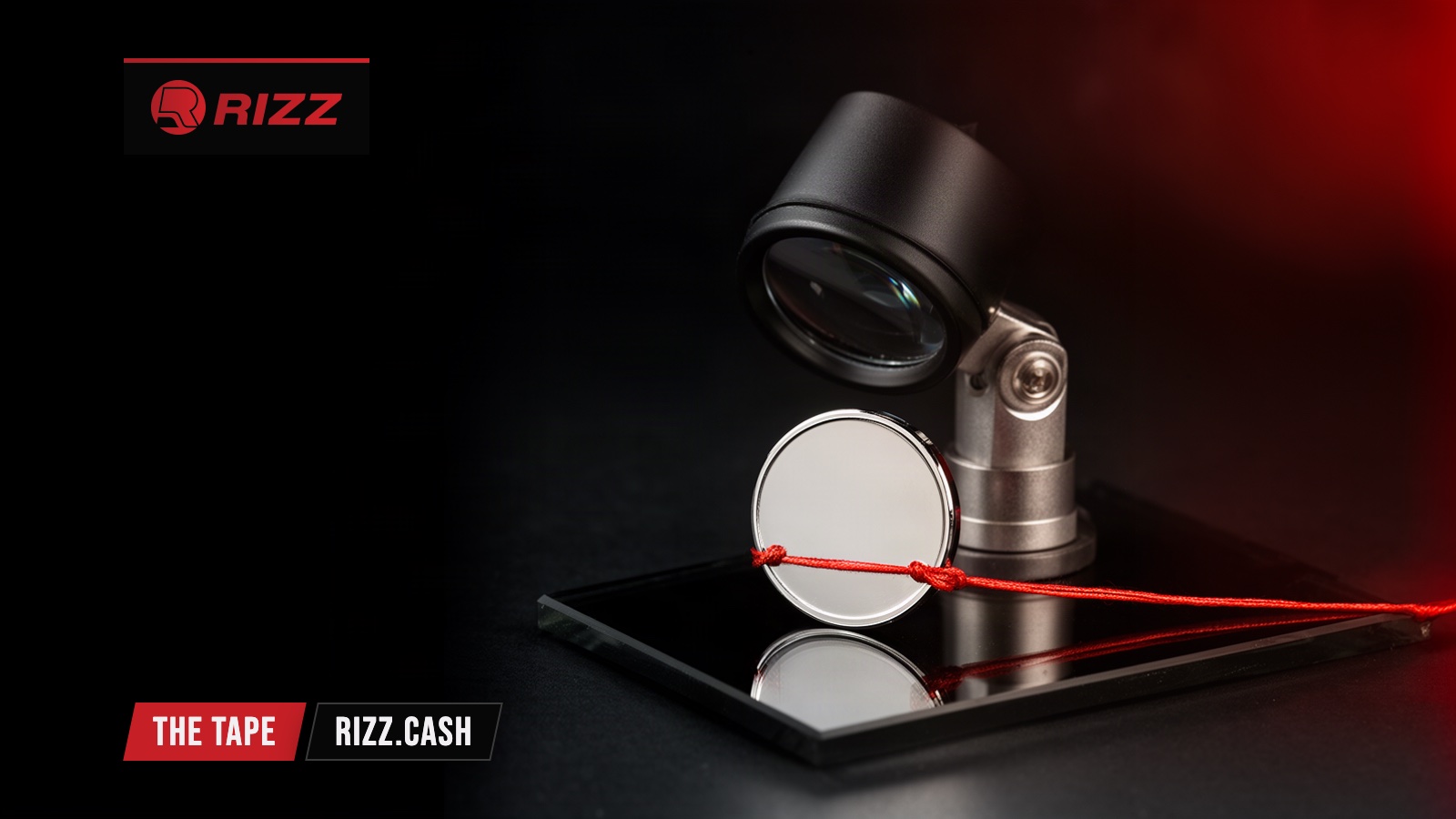 A blank chrome token on black glass with a red thread tied round it, watched by a jeweller's loupe in a dark studio.