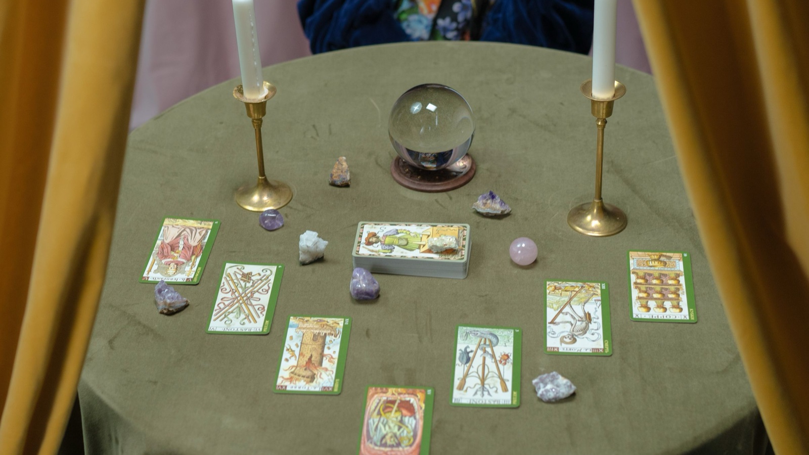 A fortune teller's table with a crystal ball, candles and laid out tarot cards