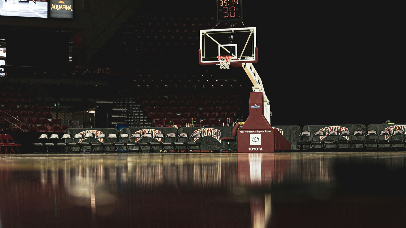 A basketball hoop and a shot clock over an empty arena floor before a game.
