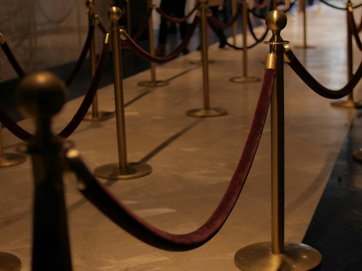 Brass stanchions linked by a velvet rope line a marble hallway.