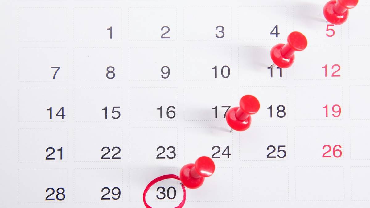 A calendar with red pushpins marking dates and one date circled.
