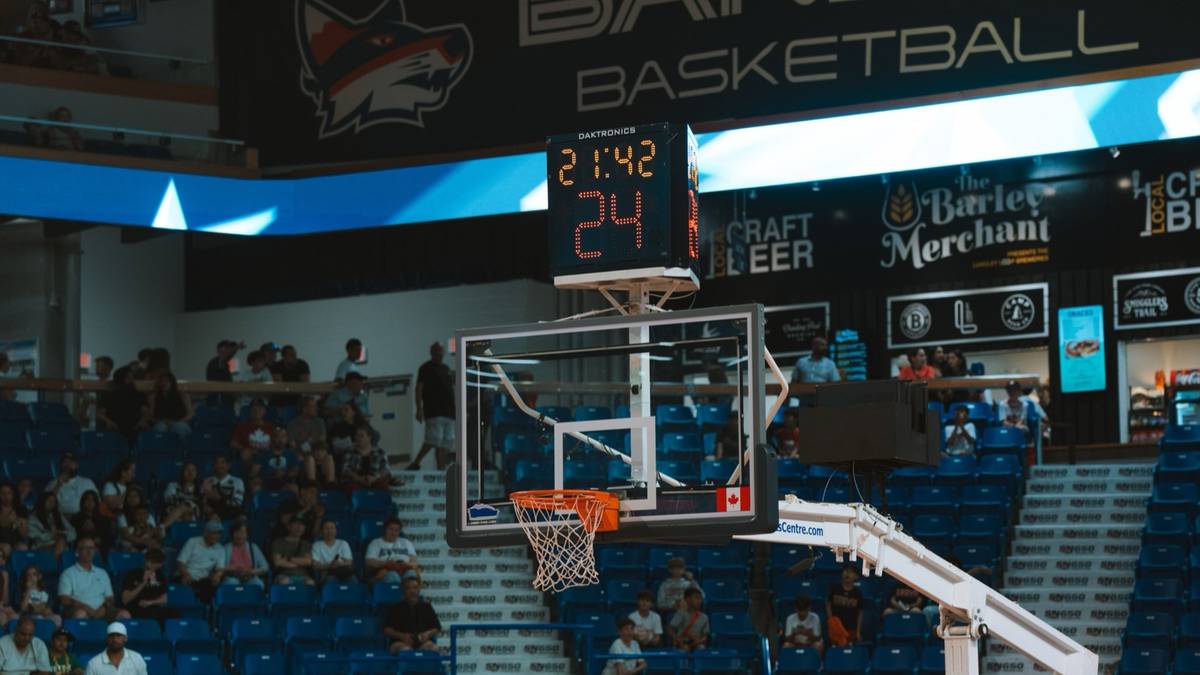 A basketball hoop and shot clock above the stands in an arena during a game.