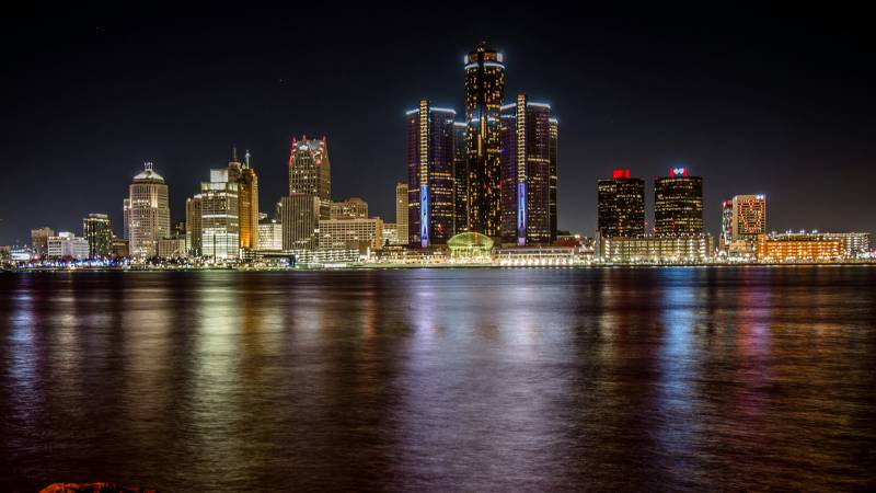 The Detroit skyline and the Renaissance Center lit up at night across the river.