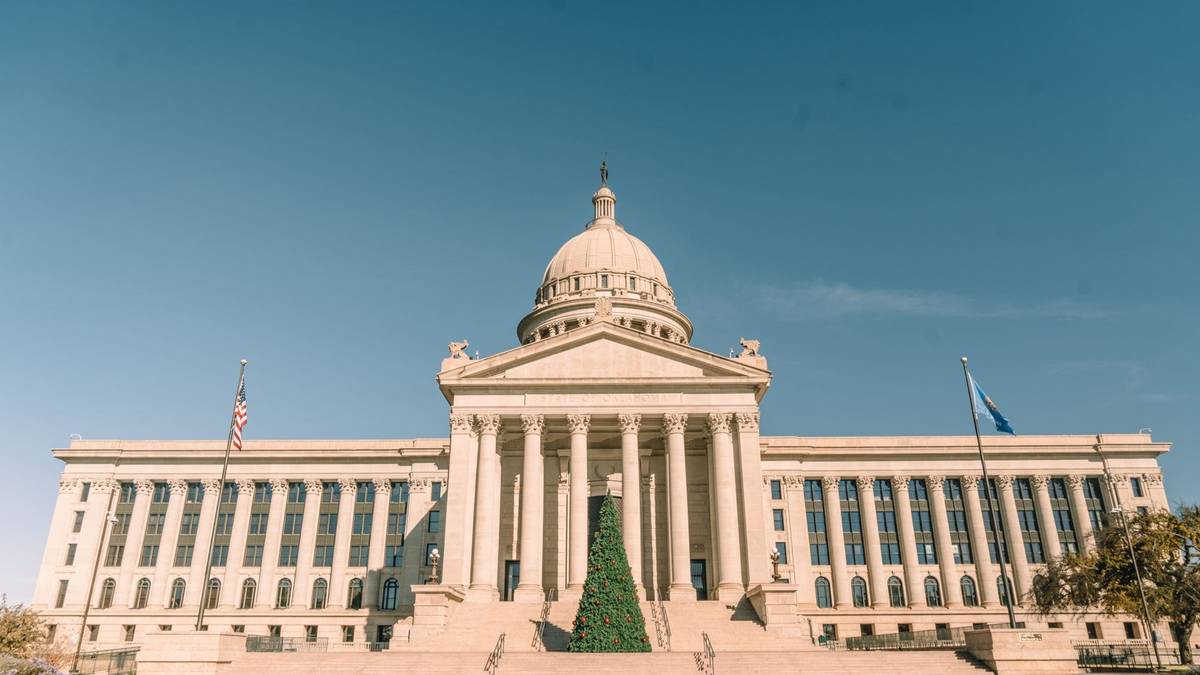 The domed state capitol building under a clear blue sky with flags flying.