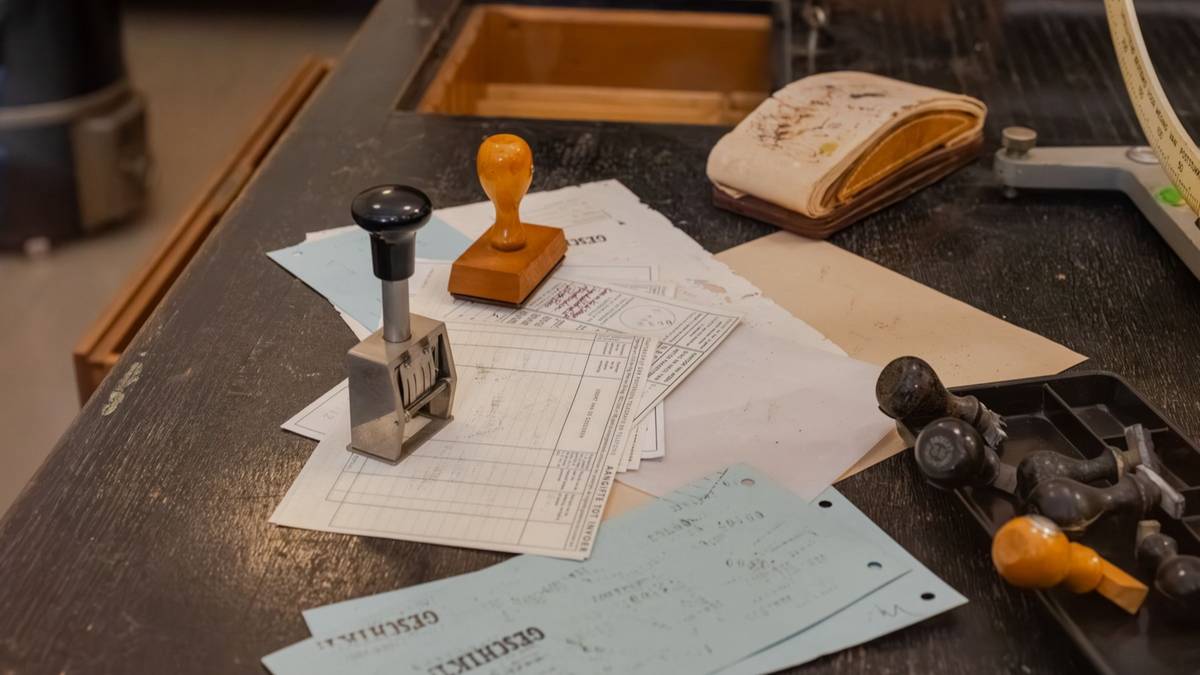 An old desk covered with paper forms, rubber stamps and a date stamper.