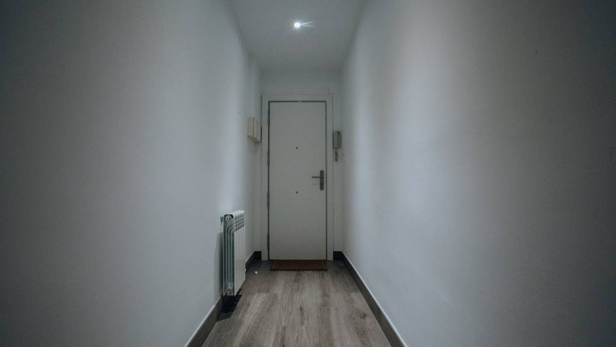 A quiet white hallway leading to a closed apartment door.