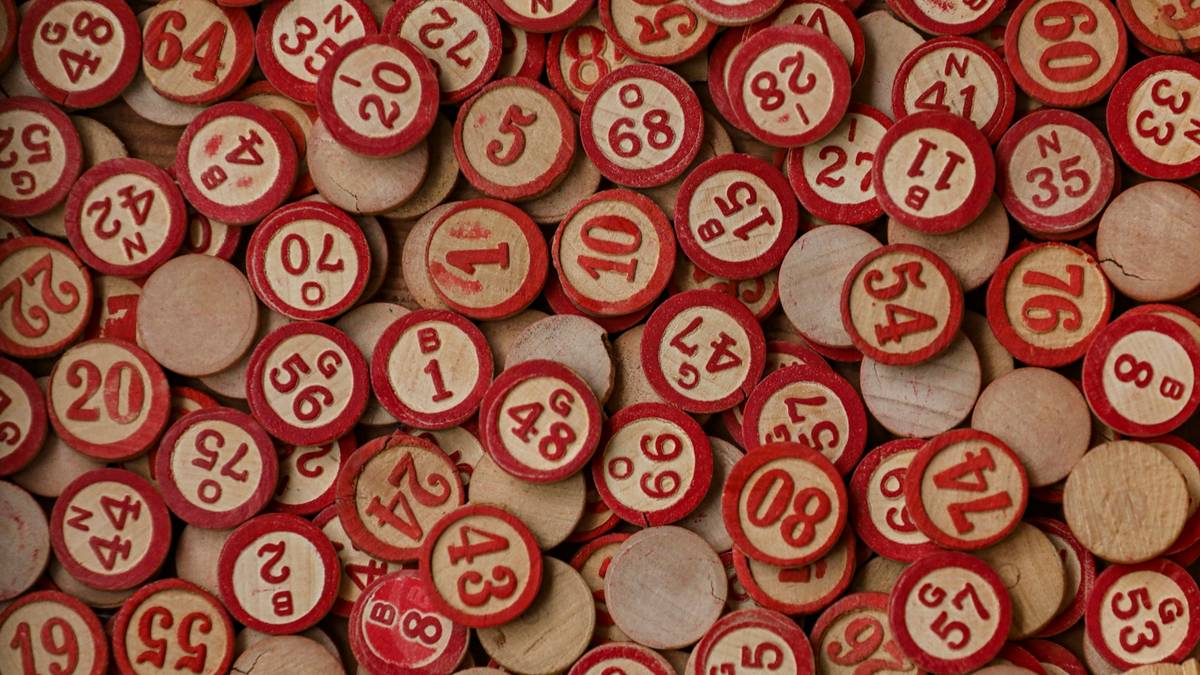 A pile of red and cream wooden number tokens, each stamped with a different number from 1 to 80.
