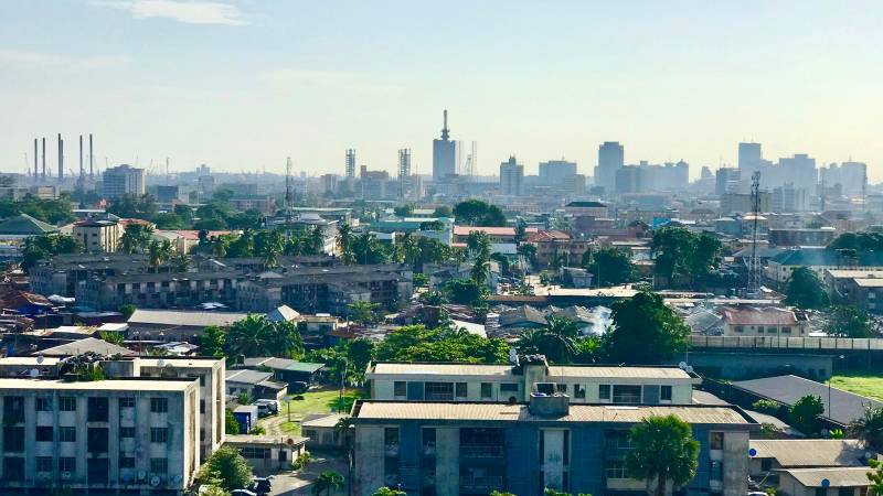 Hazy morning view over Lagos rooftops and apartment blocks toward the downtown skyline.