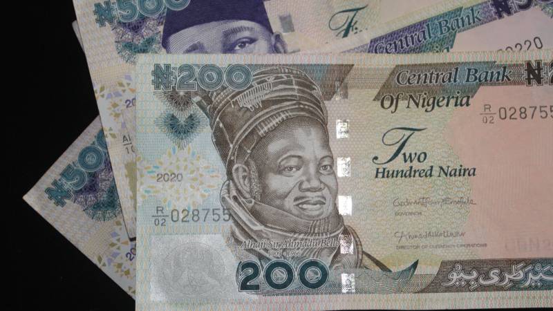 A fan of Nigerian naira banknotes with a 200 naira note in front.