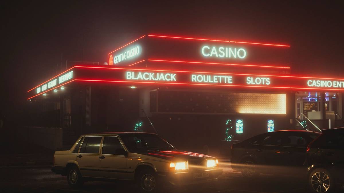 A neon-lit casino lit up at night with a car parked in front.