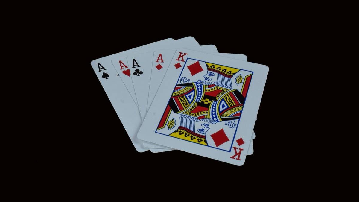 Four aces and a king fanned out on a black background.