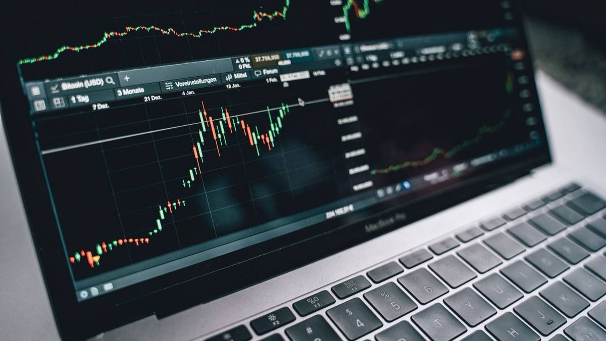 A laptop screen showing candlestick price charts from a live trading platform.
