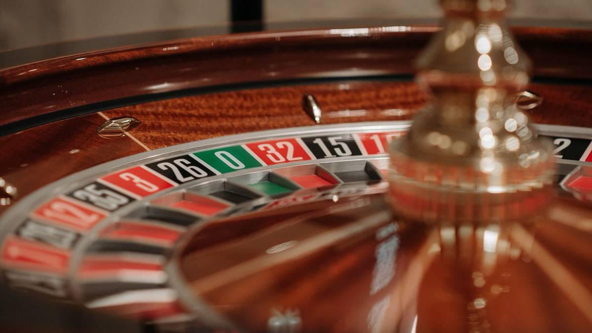 Close-up of a casino roulette wheel with the green zero pocket in focus beside red and black numbers.