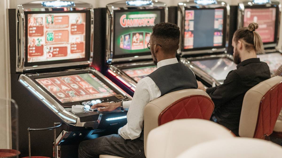 Two men seated at video gaming machines in a casino.