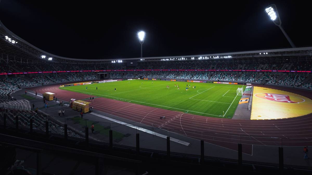 A floodlit football stadium at night with the pitch lit up.