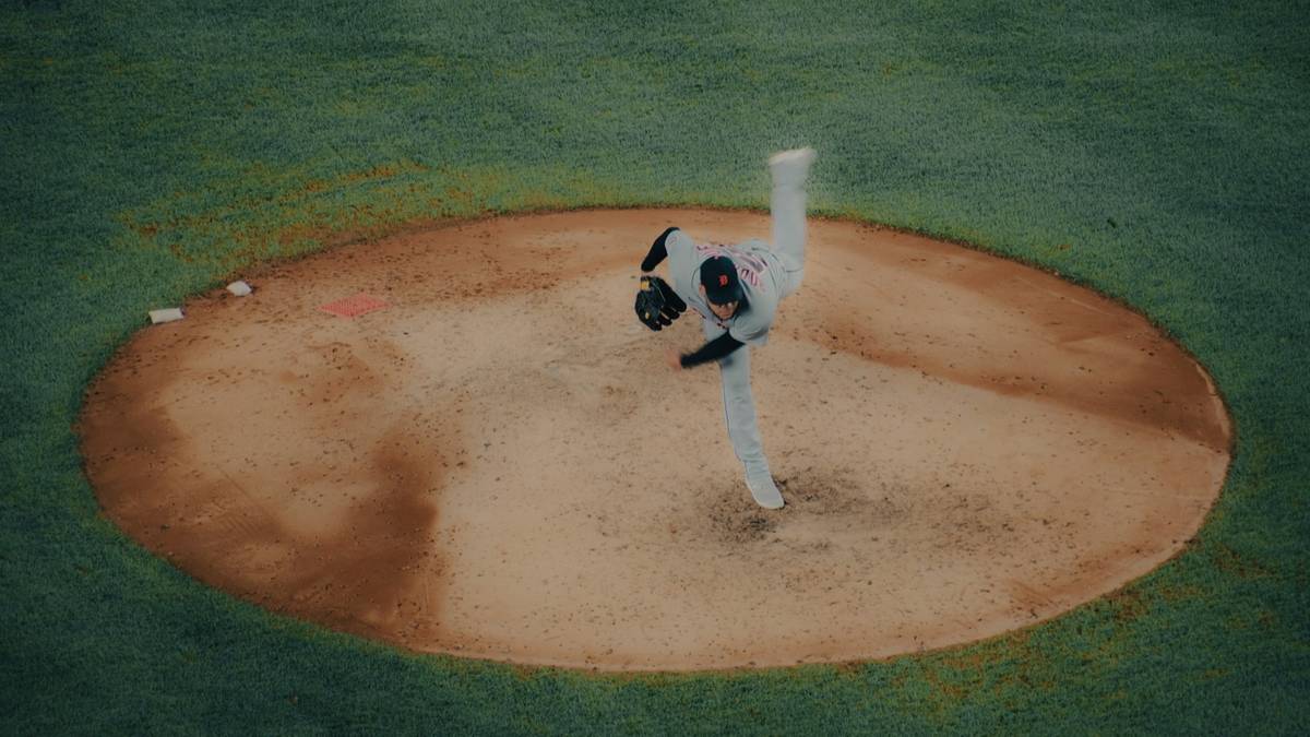 A baseball pitcher in mid delivery on the mound, seen from above.