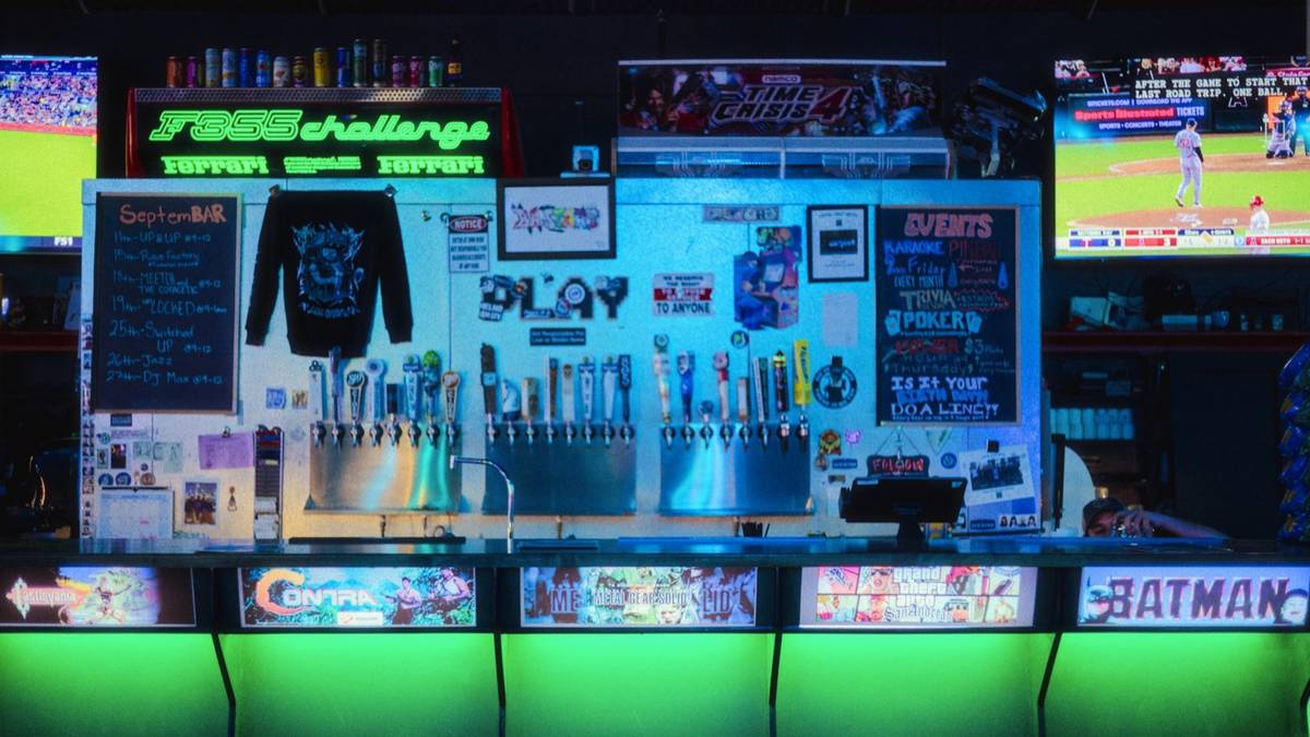 A sports bar with a glowing counter, beer taps and several screens showing games.
